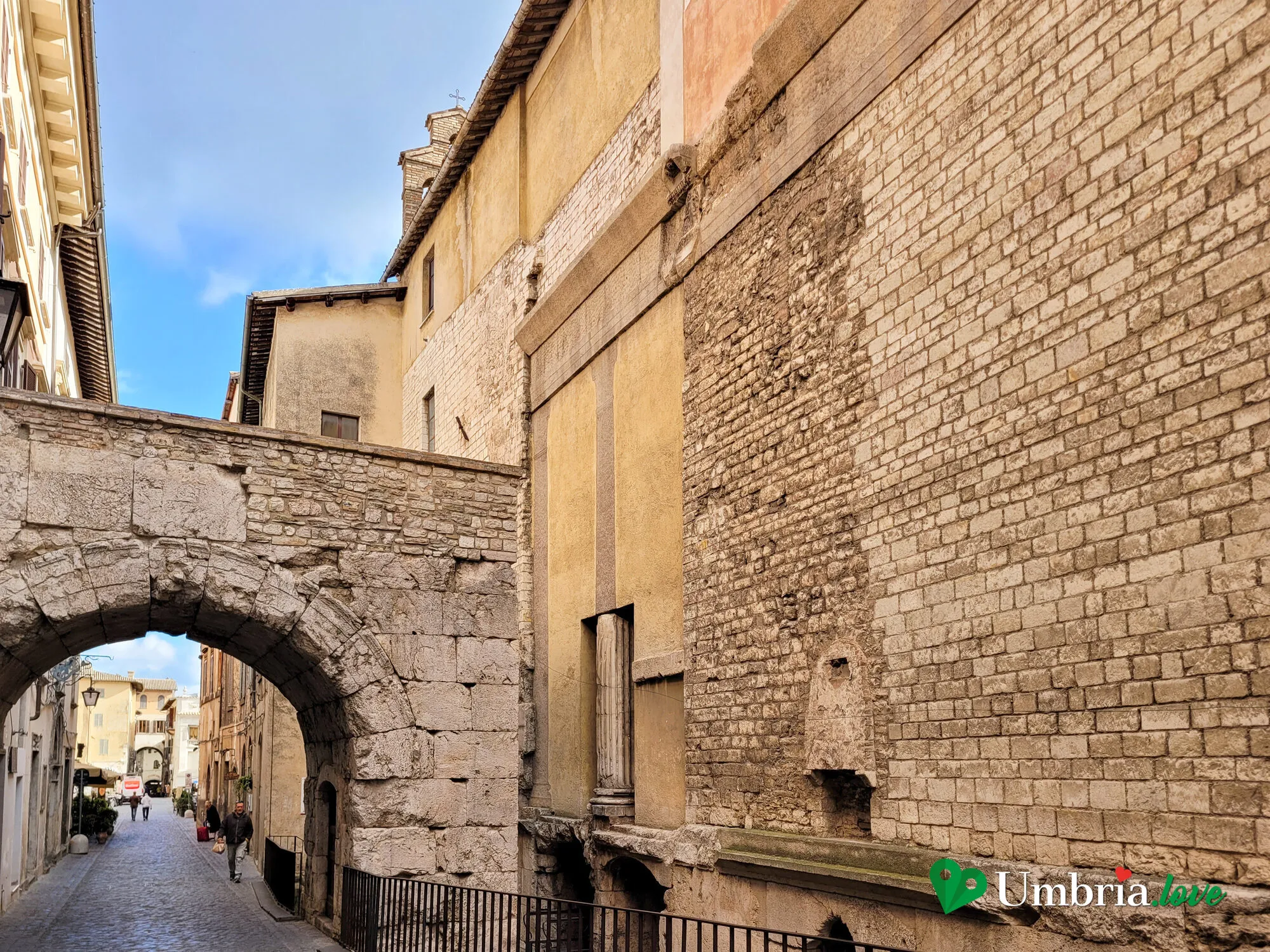 L'Arco di Druso visto dal vicolo che sale da Piazza del Mercato, incassato tra i muri in blocchi di pietra