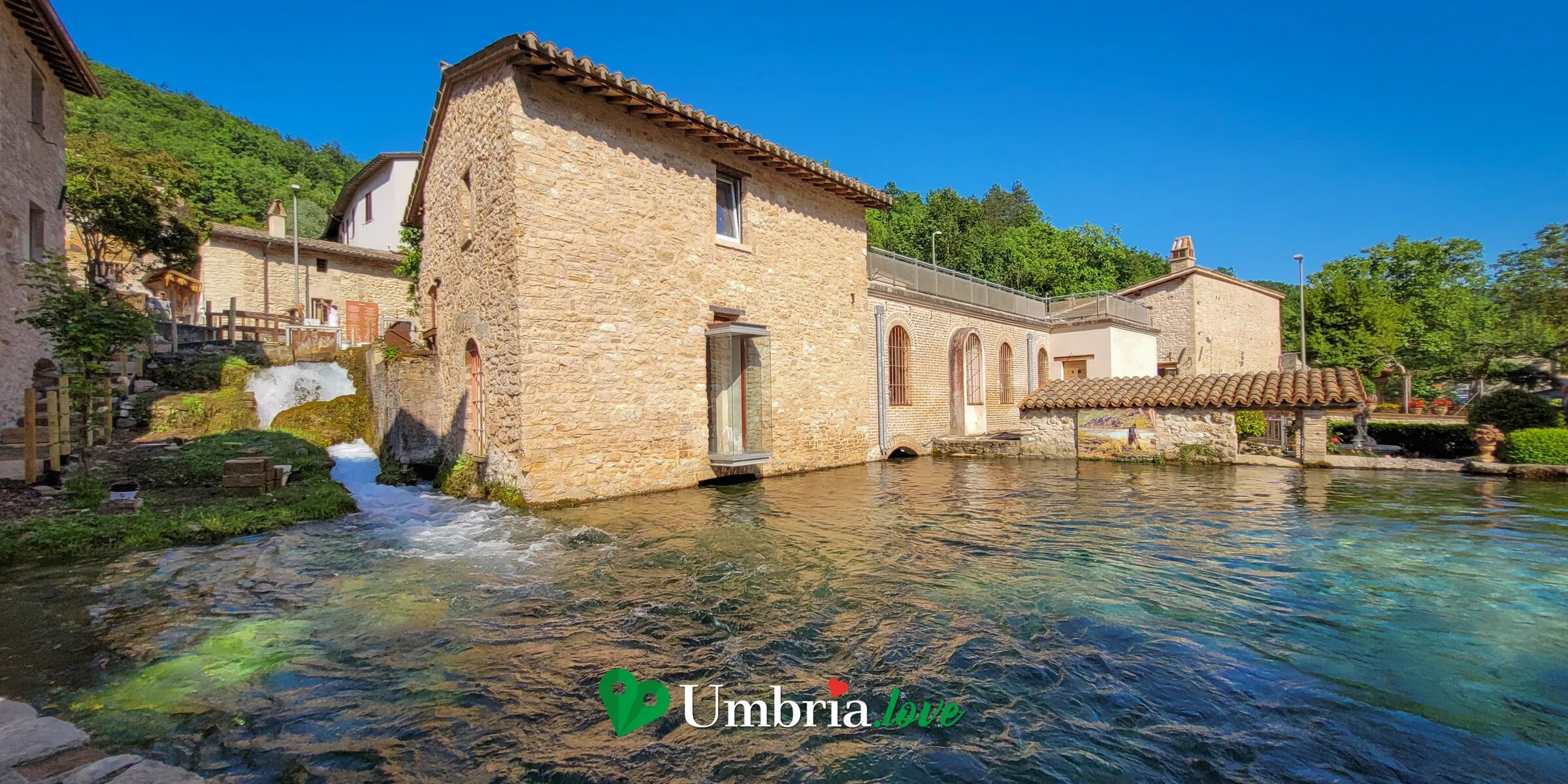 Le case di pietra di Rasiglia affacciate su un canale d'acqua limpida, con un ponticello e il bosco alle spalle