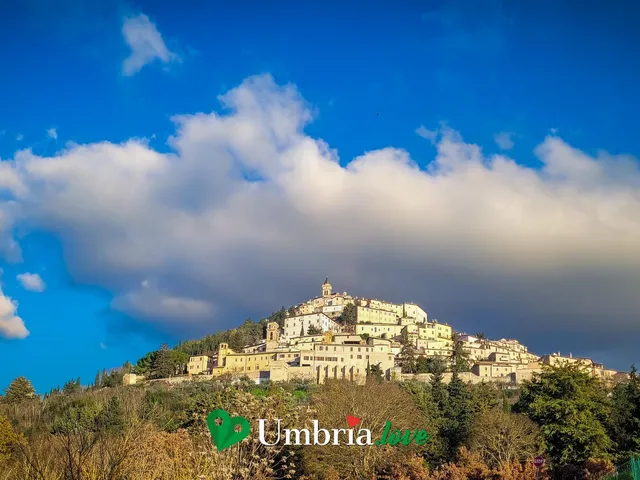 Il borgo di Trevi arroccato a spirale in cima al suo colle, circondato dagli uliveti, sotto un cielo azzurro