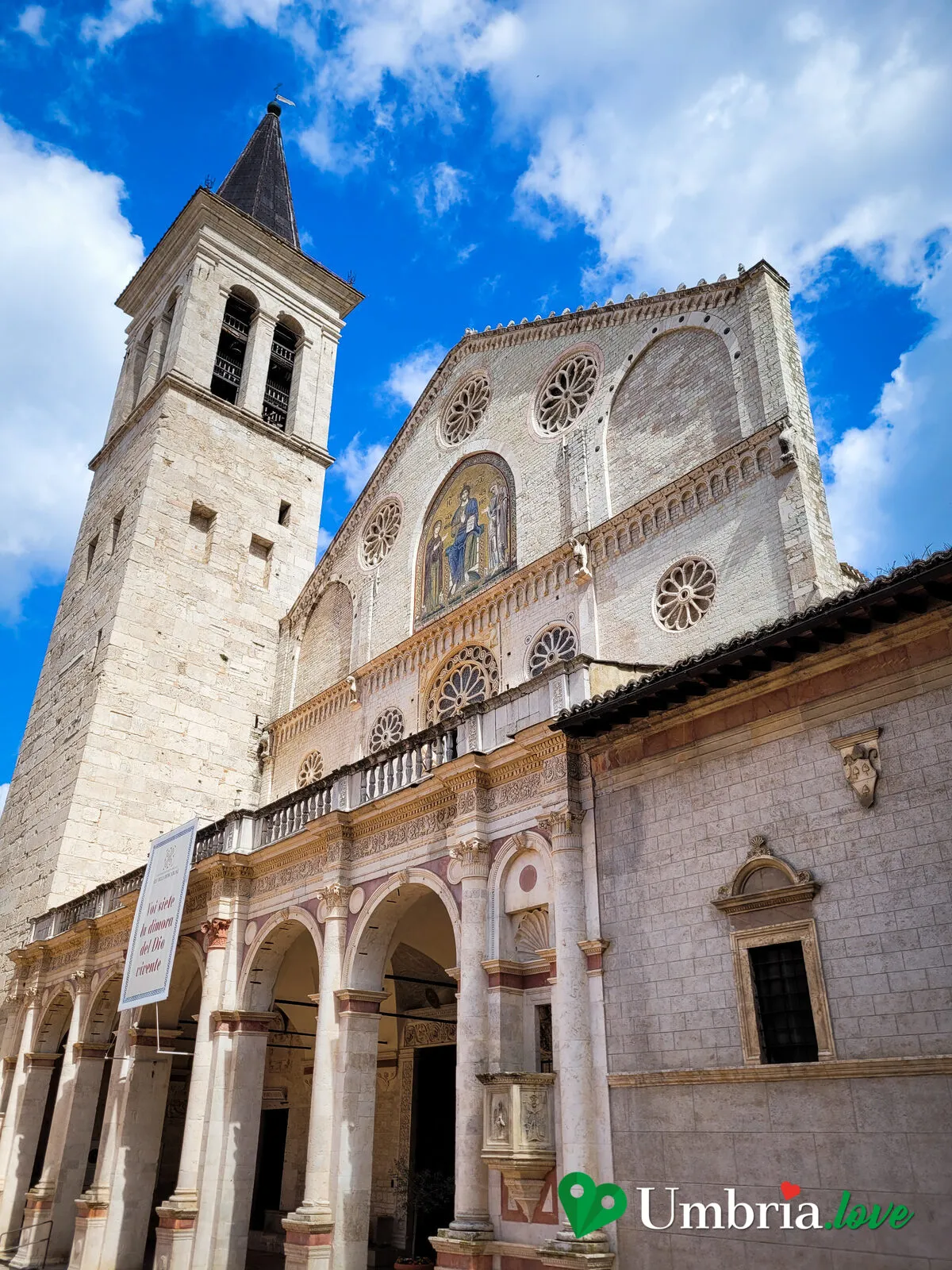 Veduta di scorcio del complesso della Cattedrale di Spoleto: il campanile in blocchi romani, la facciata e il portico affacciati sulla piazza
