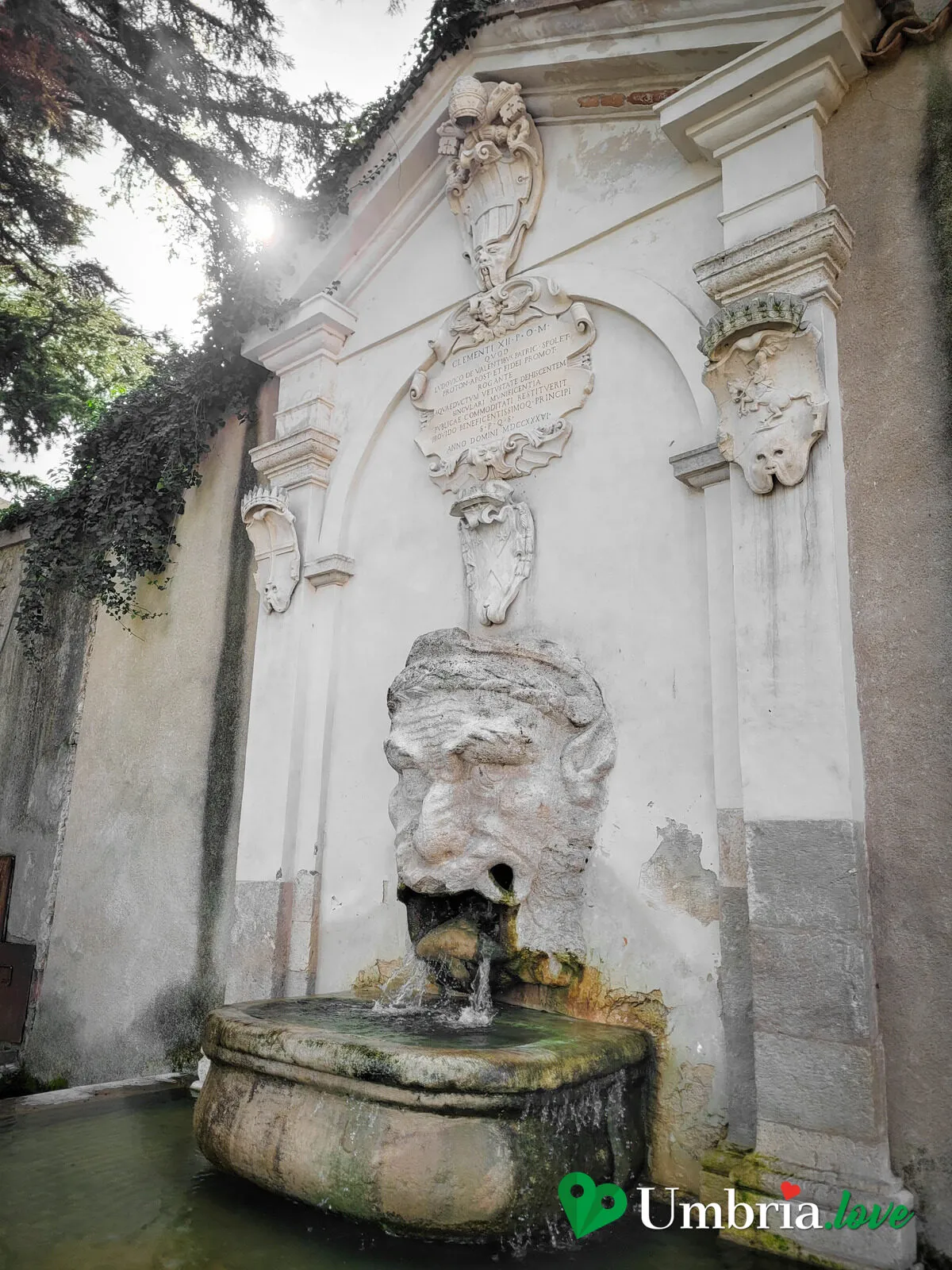 La Fontana del Mascherone di Spoleto: un grande volto grottesco di pietra incassato in una parete, con la vasca sottostante