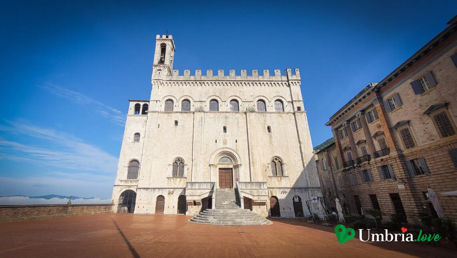 Veduta di tre quarti del Palazzo dei Consoli di Gubbio dalla Piazza Grande, con i palazzi affacciati sulla piazza pensile