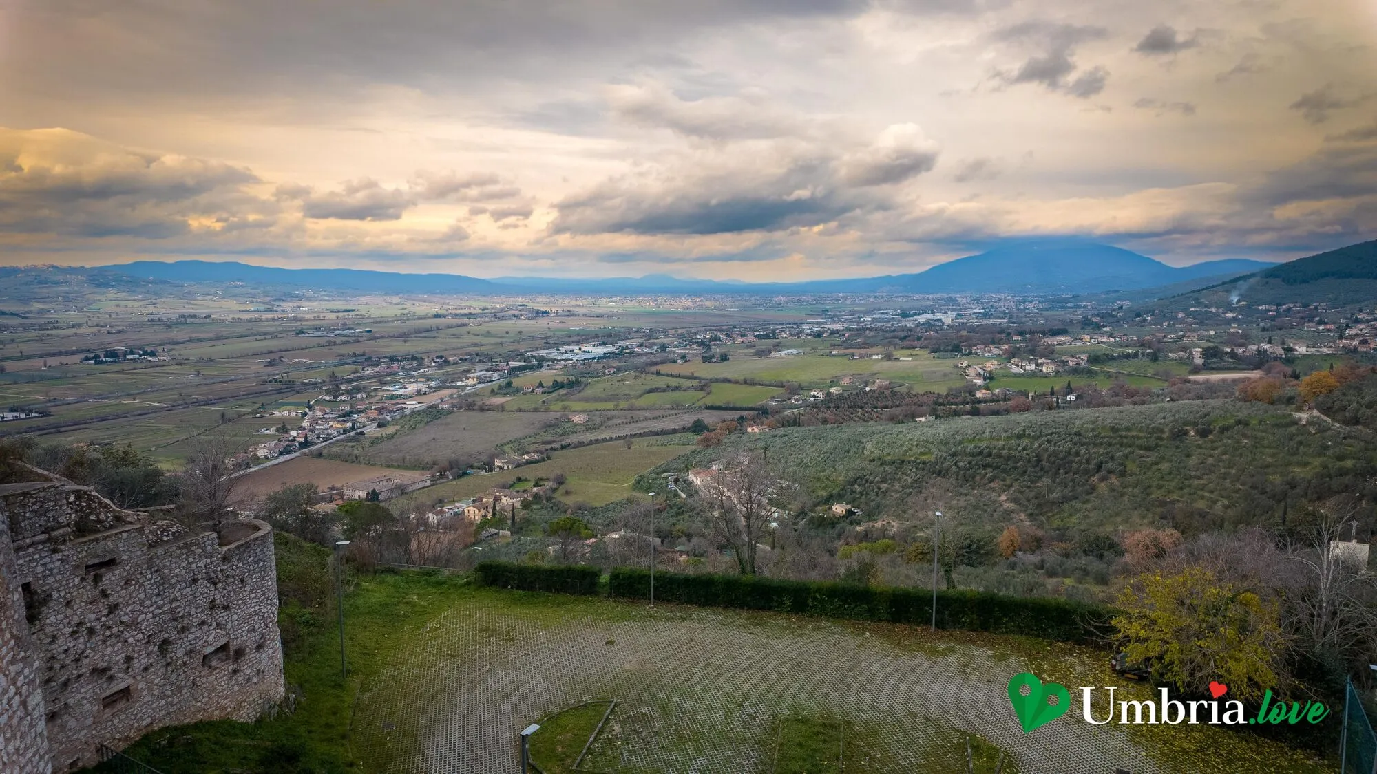 Il panorama sulla valle umbra dal colle di Trevi, al tramonto, con i resti delle mura in primo piano