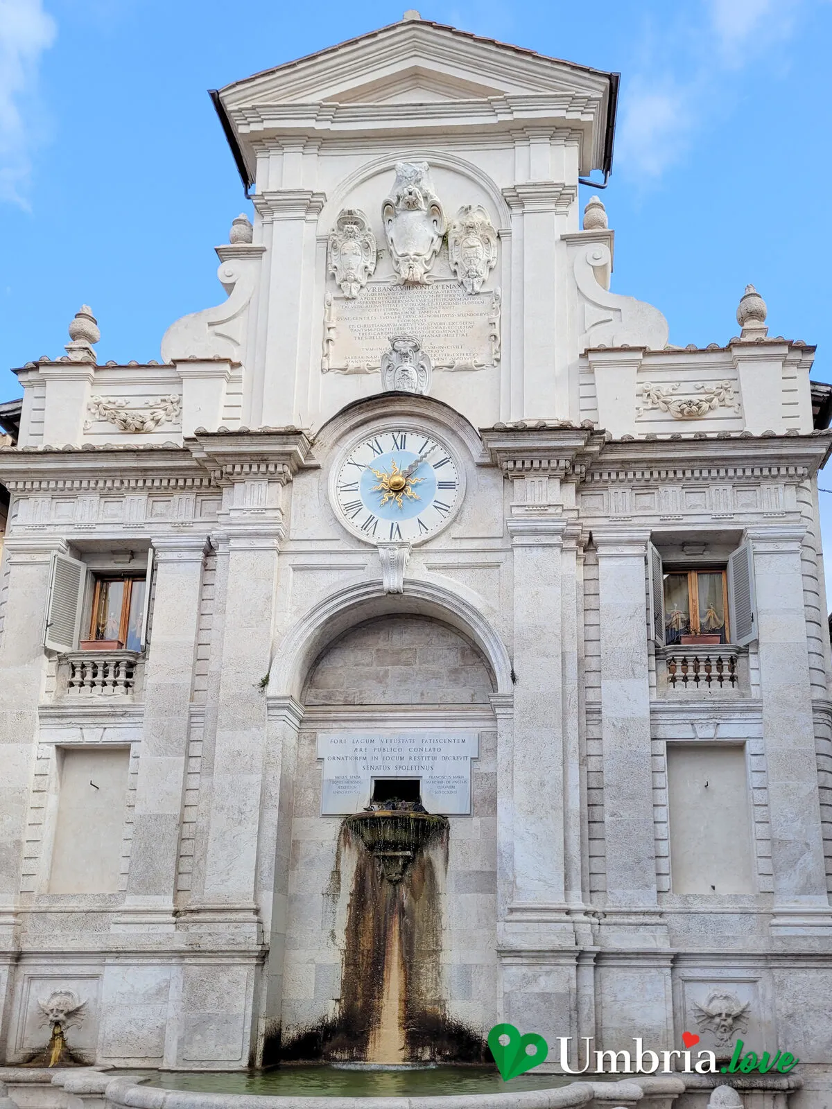 La fontana settecentesca di Piazza del Mercato a Spoleto, addossata alle case sotto un orologio