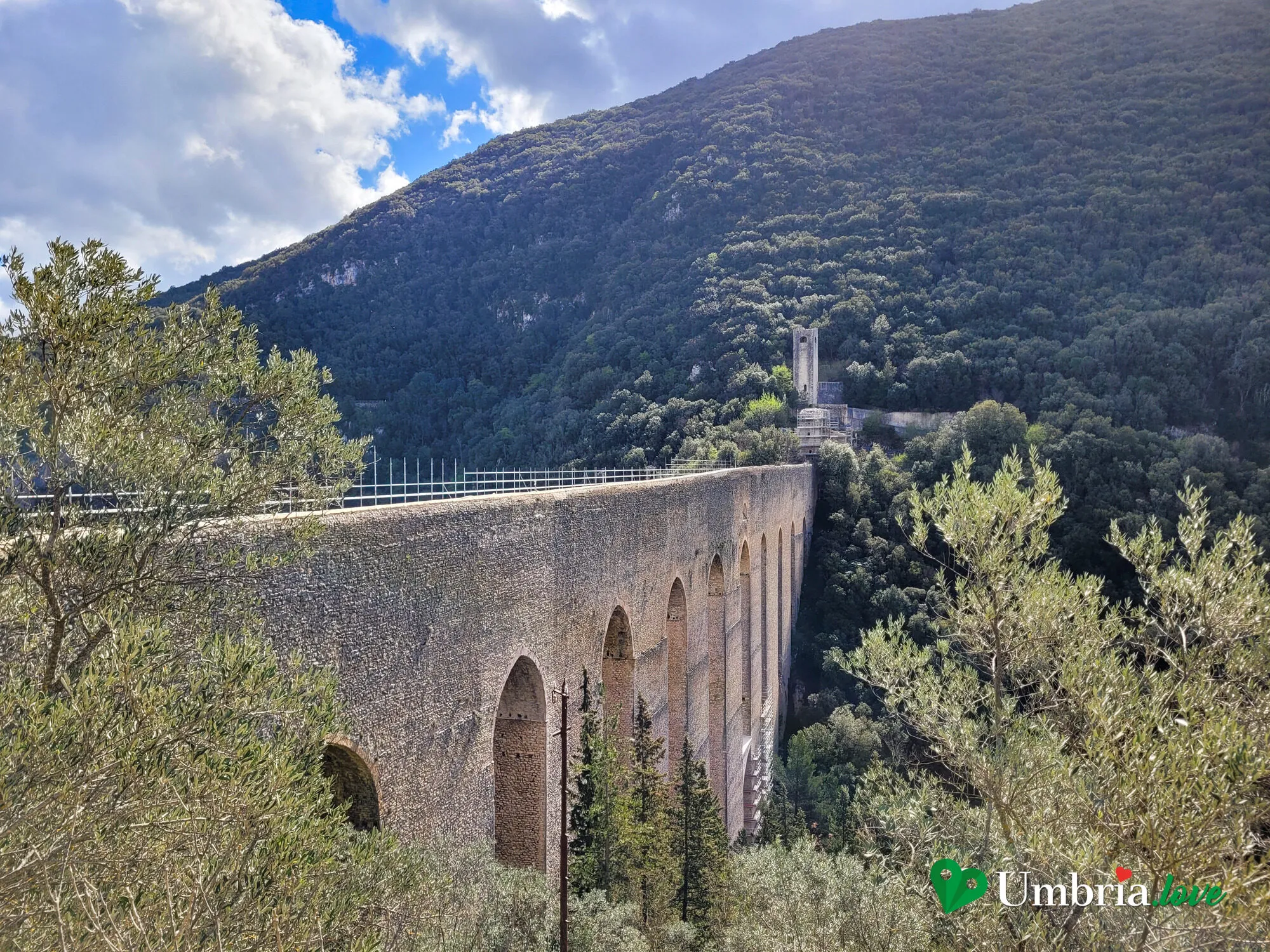 Il Ponte delle Torri di Spoleto visto quasi di fronte dal Giro dei Condotti: le alte arcate ogivali sopra la gola boscosa, con il Fortilizio dei Mulini sul crinale
