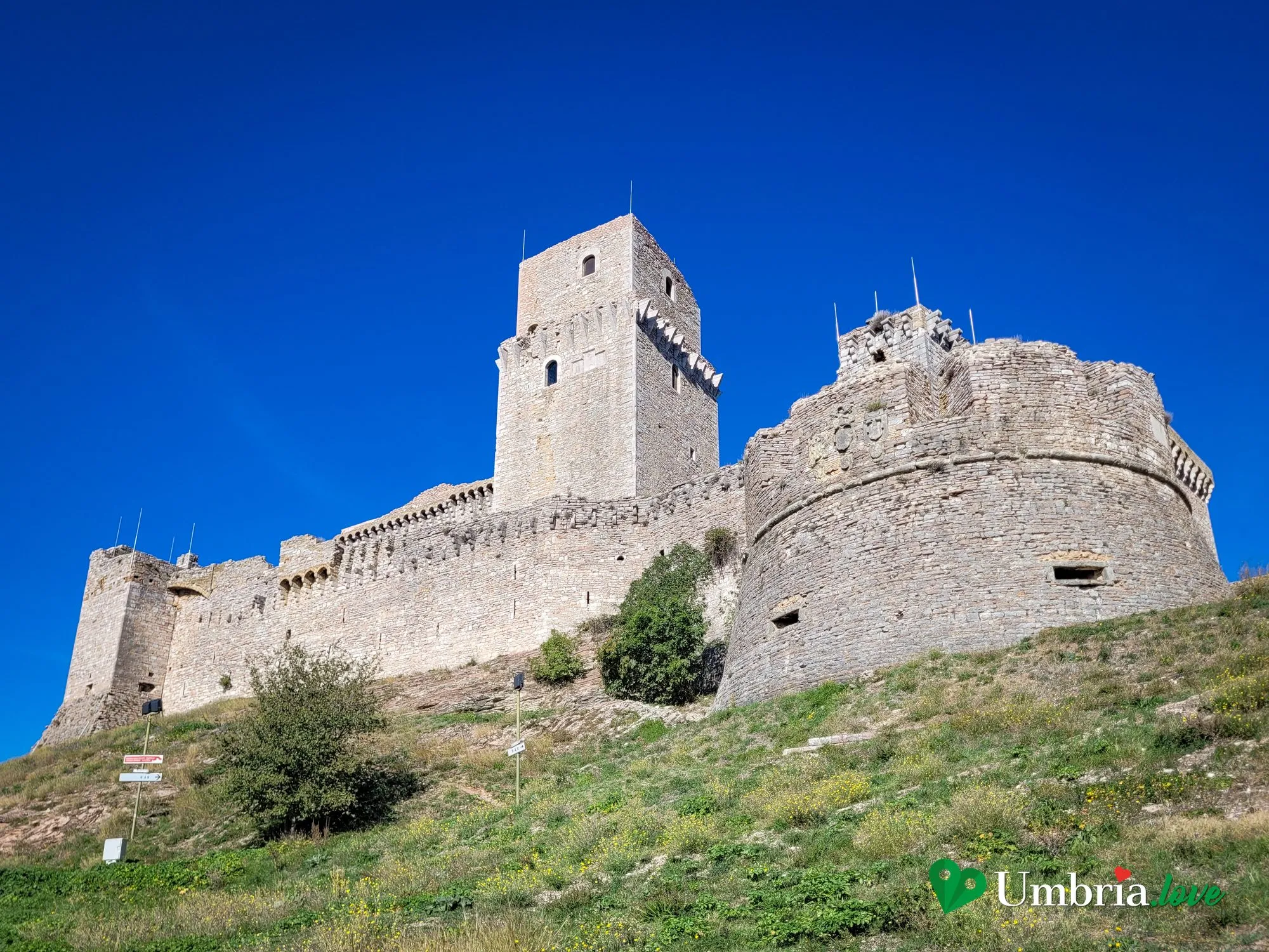 La Rocca Maggiore di Assisi: il mastio e il torrione cilindrico visti dal prato in salita