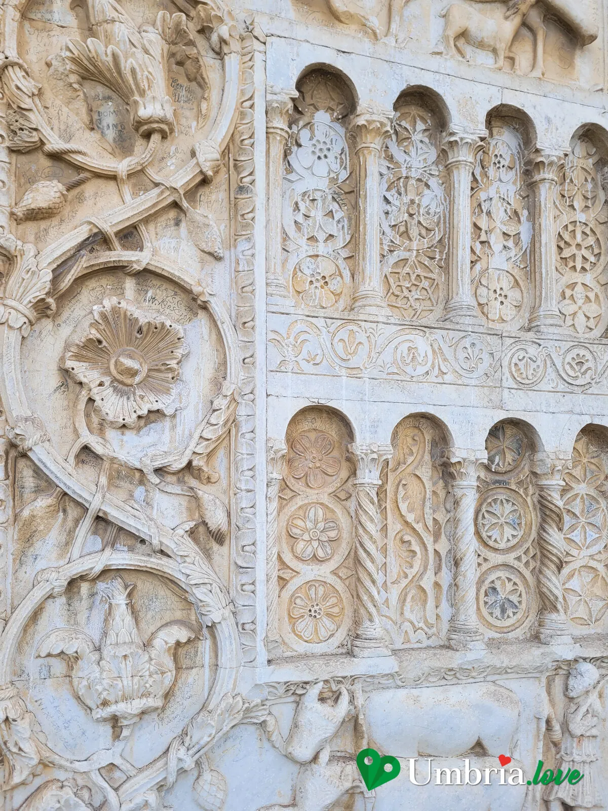 Dettaglio dei pannelli scolpiti sulla facciata di San Pietro a Spoleto: figure di animali, scene di caccia e favole medievali