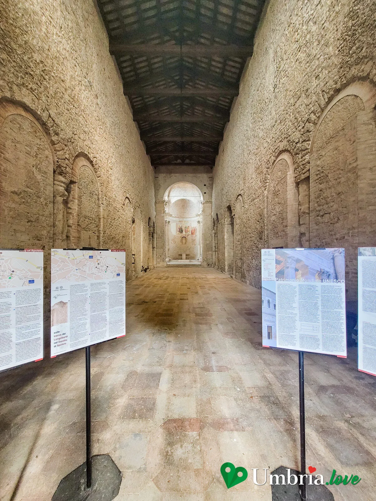 L'interno spoglio della basilica di San Salvatore a Spoleto, con le colonne romane di reimpiego e il presbiterio rialzato