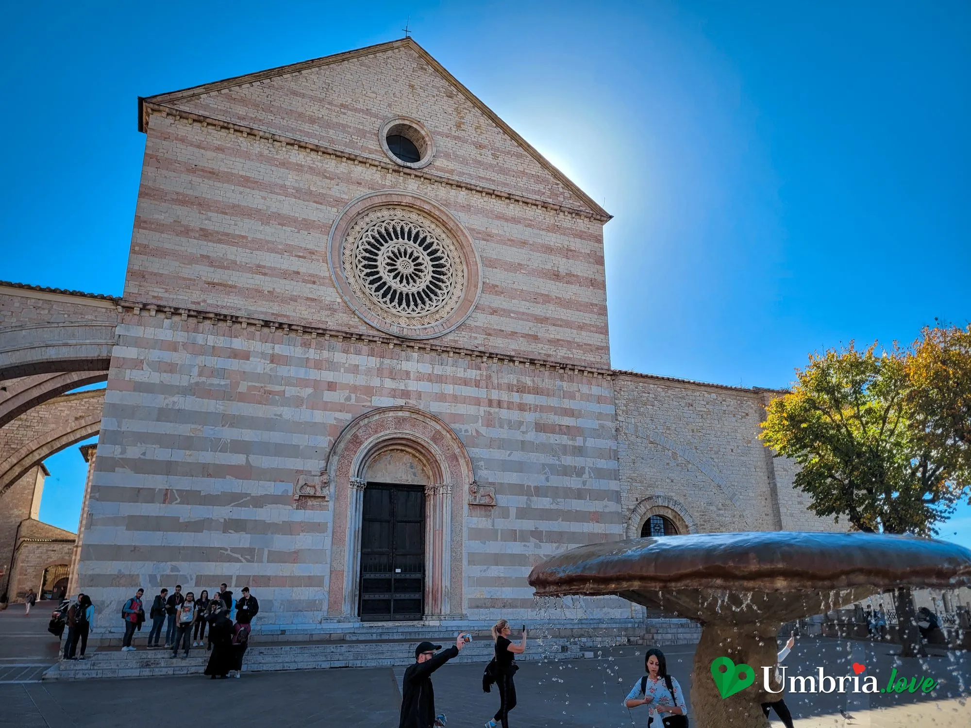 La facciata a fasce bianche e rosa della Basilica di Santa Chiara ad Assisi, con il grande rosone