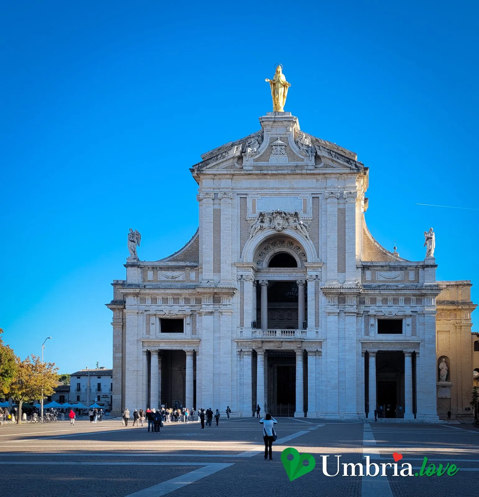 La facciata monumentale della Basilica di Santa Maria degli Angeli ad Assisi, sormontata dalla statua dorata della Madonna
