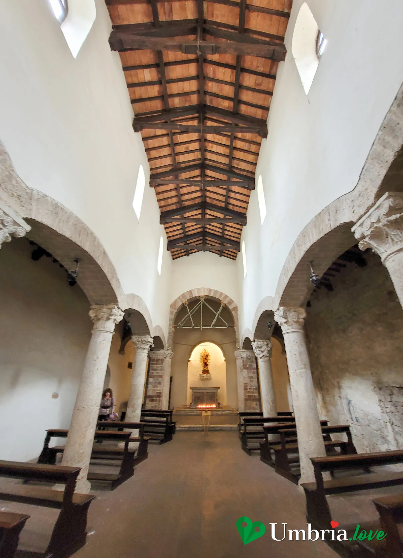 L'interno di Santa Maria Impensole a Narni: tre navate, colonne in pietra e il tetto a capriate di legno