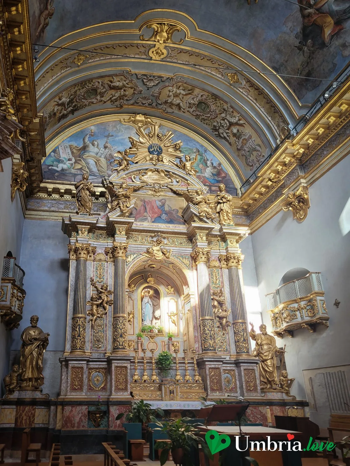 L'interno barocco della chiesa di Santa Maria sopra Minerva ad Assisi, con l'altare dorato e l'abside affrescata dentro il tempio romano